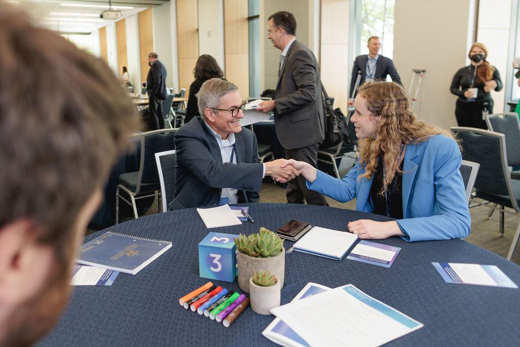 attendees shake hands at a table