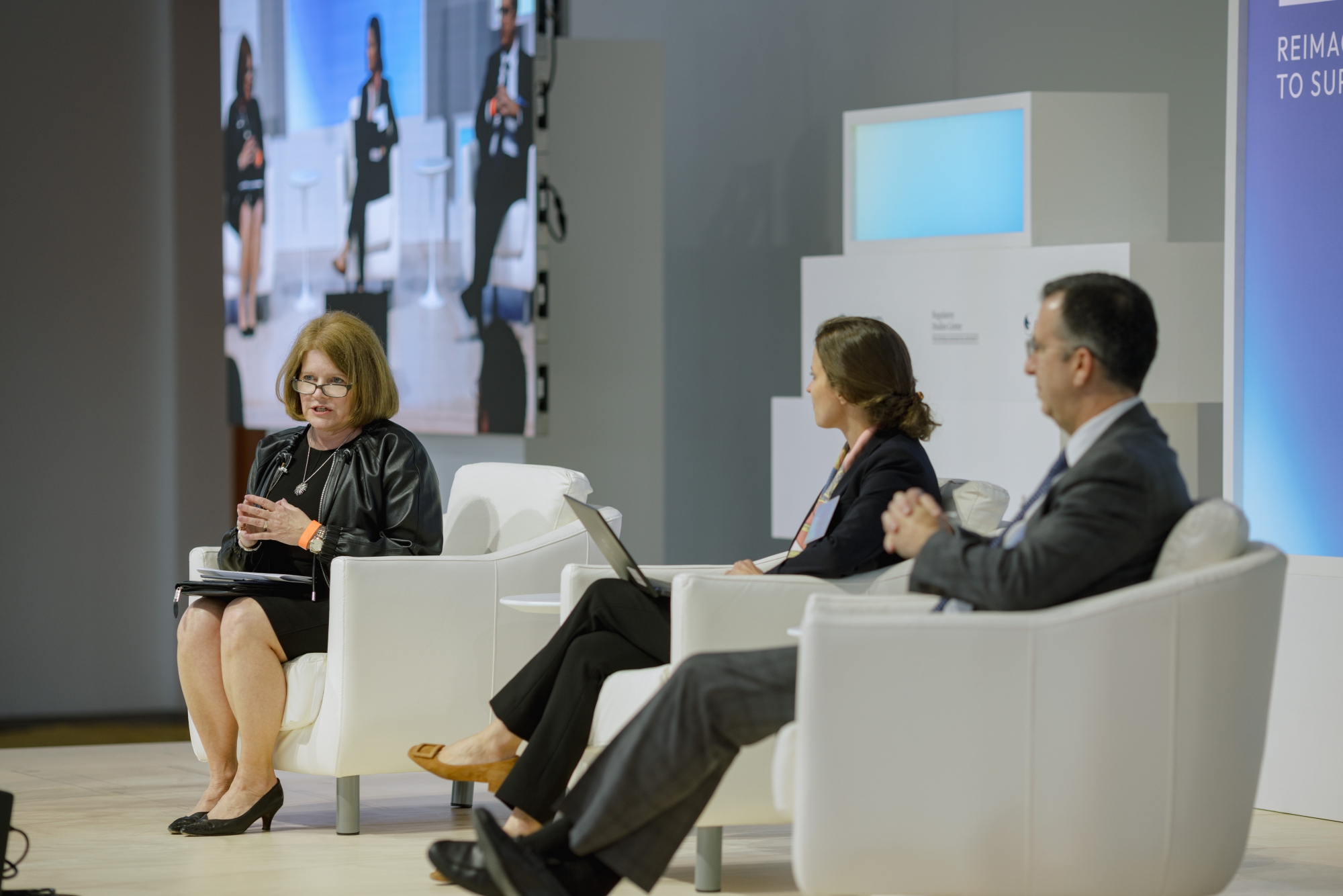 three people seated on stage