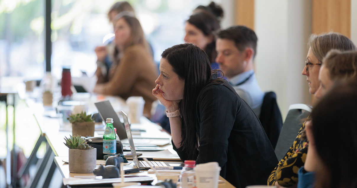 A woman at an Agile Governance workshop listening with her chin on her hand