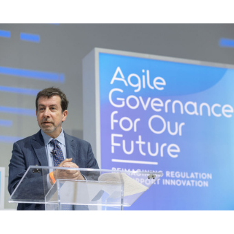 Michael Mandel speaking from podium