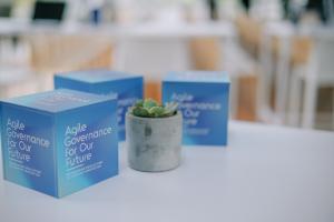 Photo of a plant and three paper boxes with event logo on each side