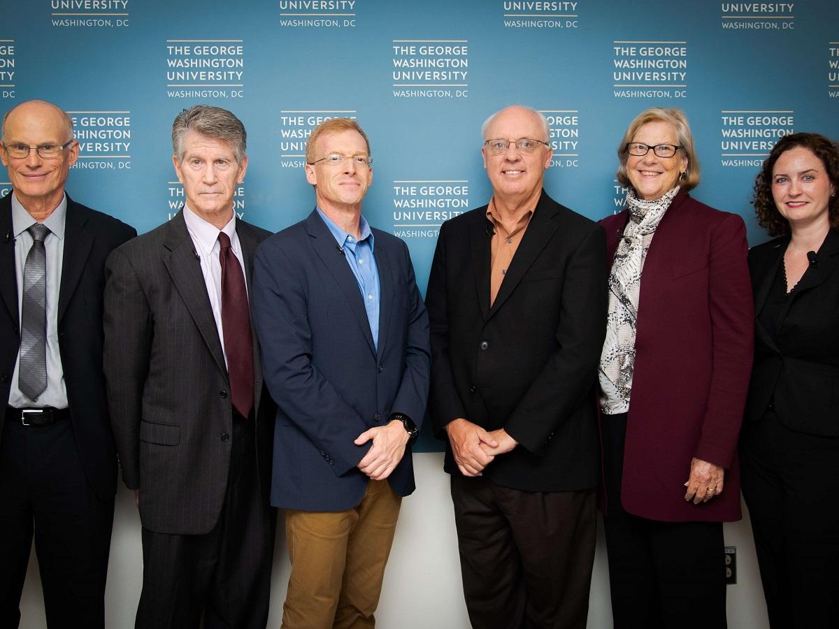 Panel One participants standing in front of a GW banner.
